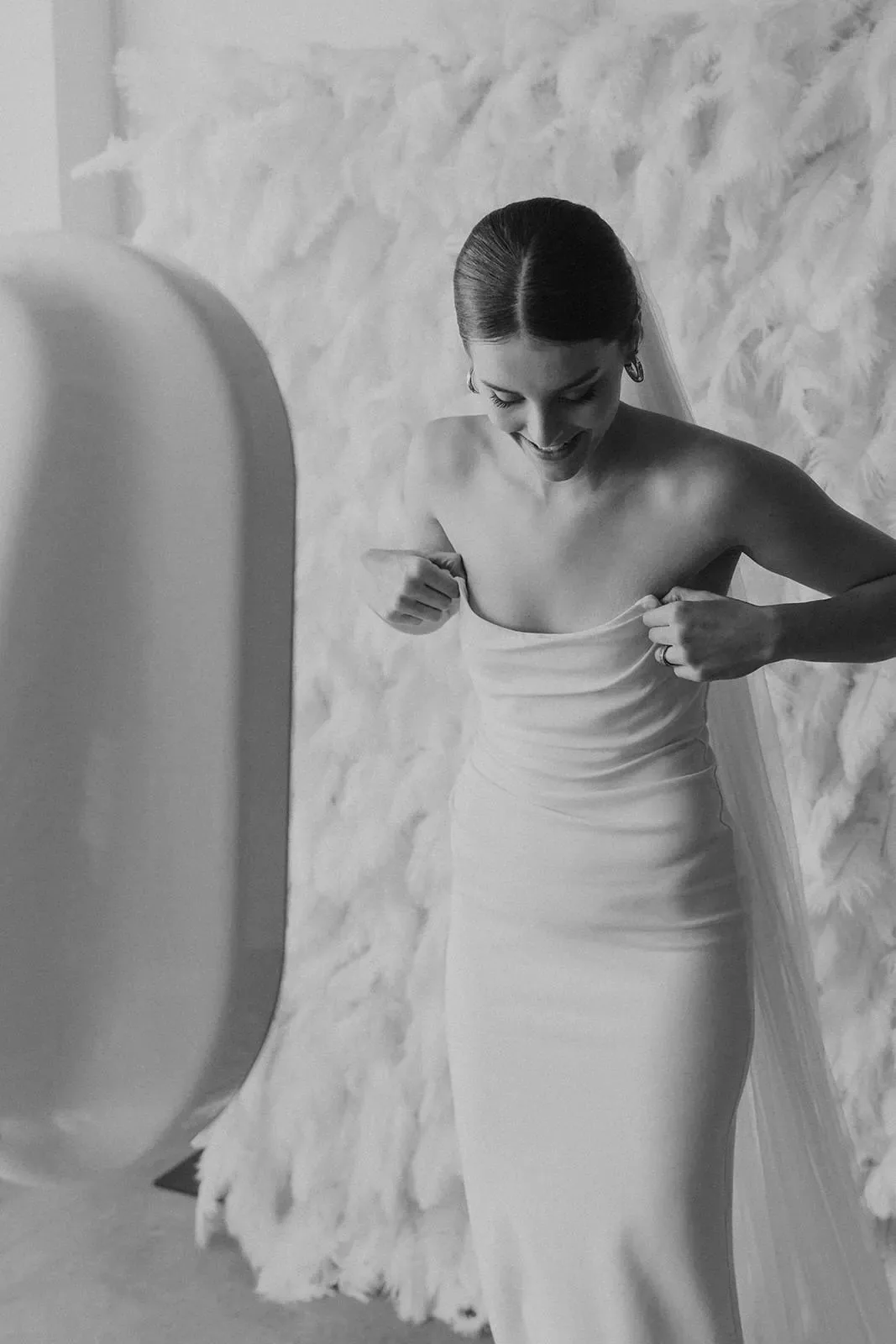 Guest posing against a soft white textured backdrop beside an open-air photo booth