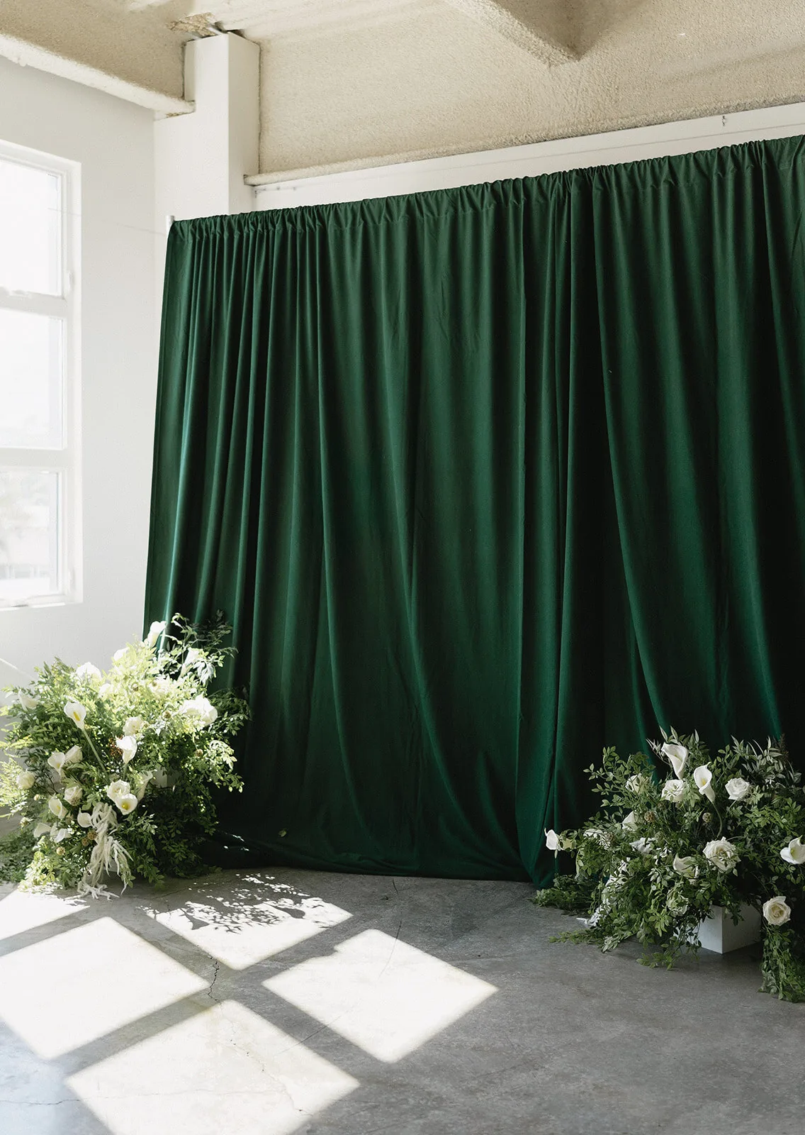 Draped fabric backdrop styled with floor floral arrangements