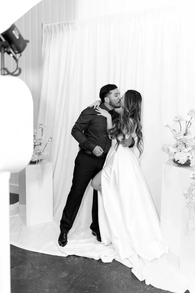 Couple laughing together in front of a white draped backdrop