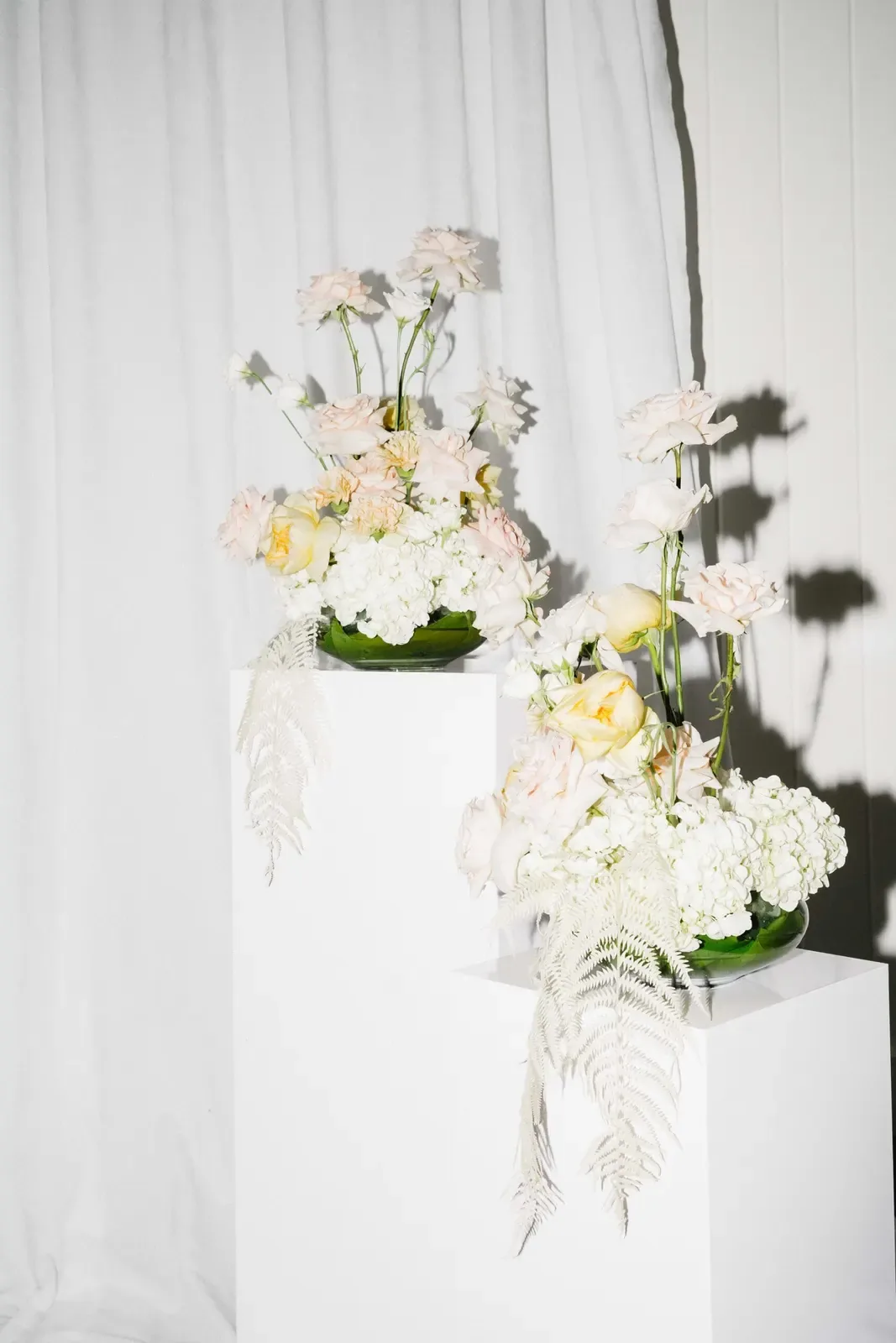 Floral arrangement suspended against a white drapery backdrop